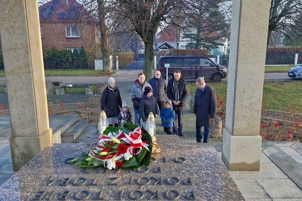 grupa osób składa wieniec przed pomnikiem