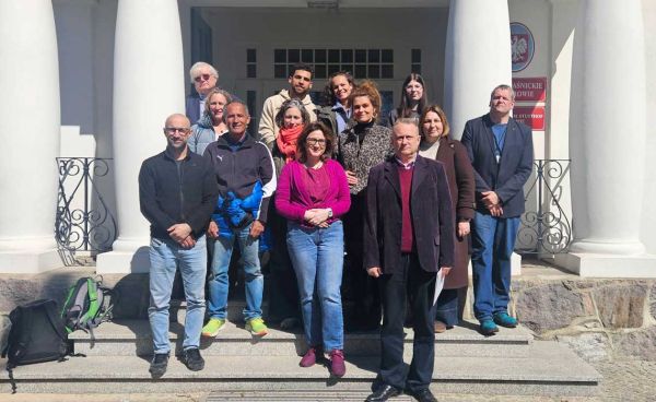 pracownicy muzeum z gośćmi pozują do zdjęcia przed muzeum