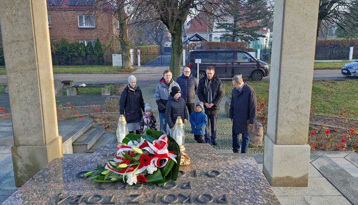 grupa osób składa wieniec przed pomnikiem